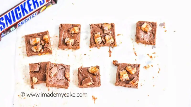 snickers fudge slices on a white parchment paper