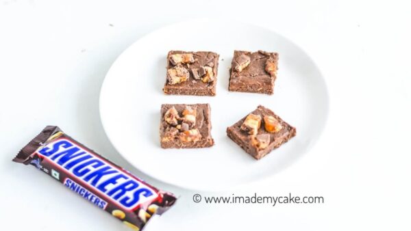 four snickers fudge slices on a white plate