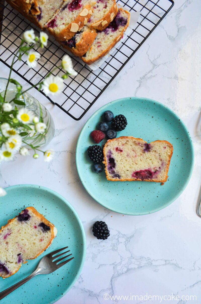 Slices of triple berry cake on a plate with berries